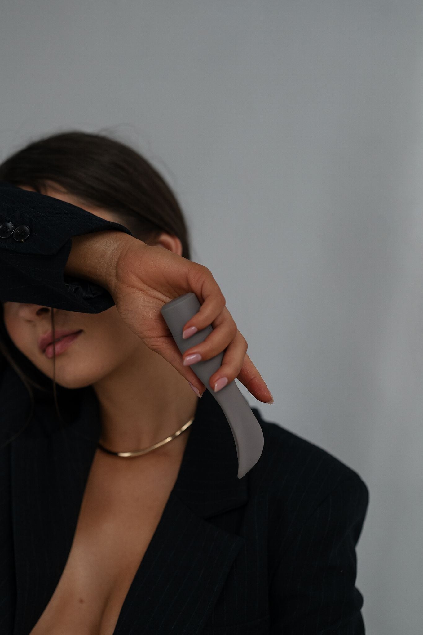 Folia - Naago. External sex toy held by hand in dim lighting, designed for personal pleasure and intimate wellness