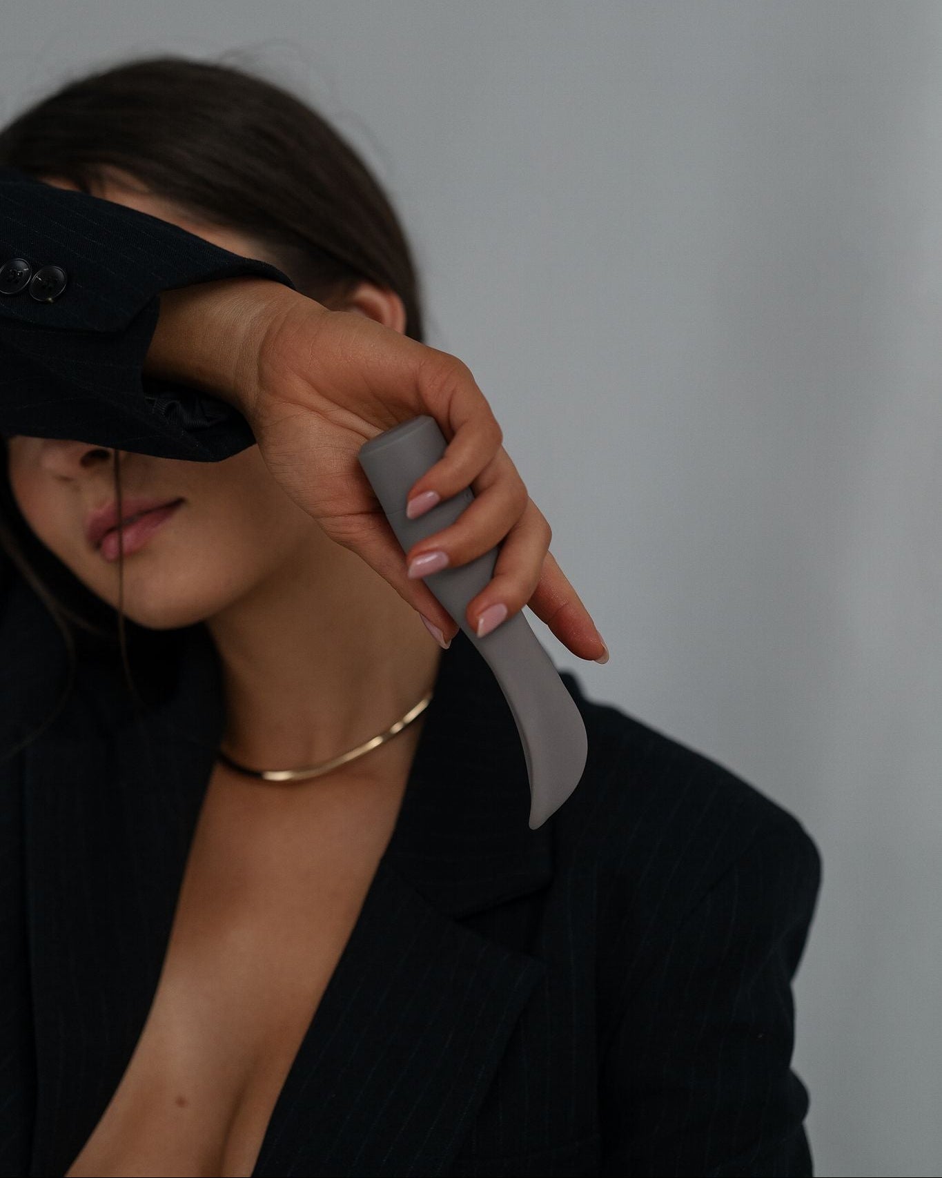 Folia - Naago. External sex toy held by hand in dim lighting, designed for personal pleasure and intimate wellness