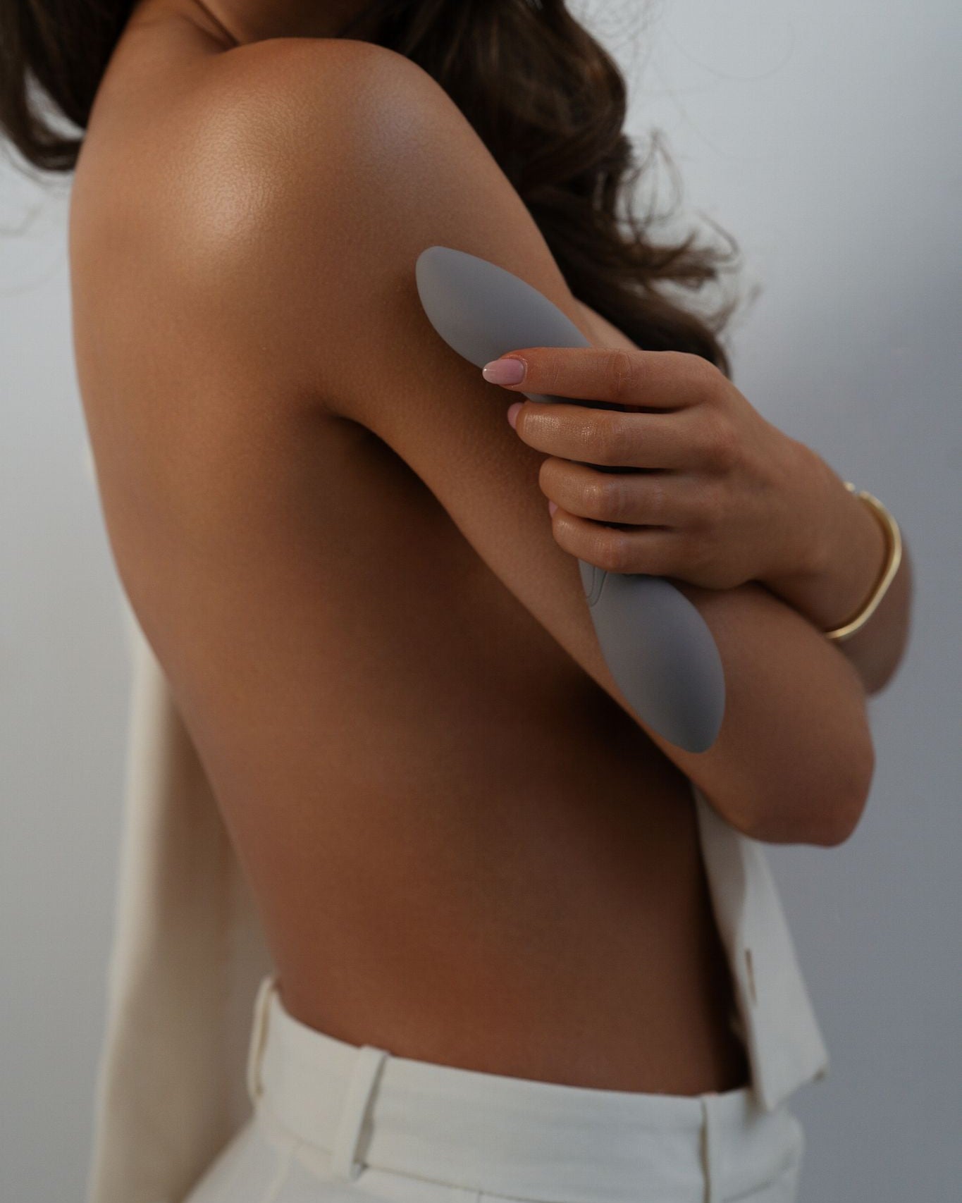 Nubia - Naago. Sleek G-spot sex toy held near body by model, designed for internal stimulation and intimate self-care